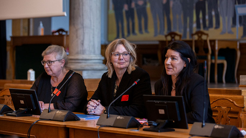 3 kvinder sidder ved et podie i en sal på Christiansborg